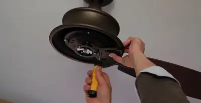 Electrician installing ceiling fan mounting bracket and fixture in Lakeland, FL